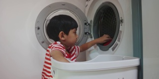 亚洲男孩在洗衣机里洗脏衣服。