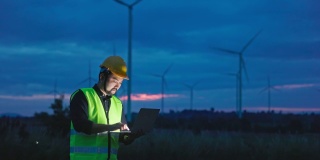 黄昏时分使用笔记本电脑在风力发电领域生产可再生能源、清洁能源或环境保护概念的电力。