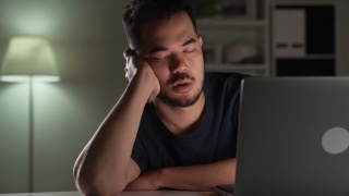 工作过度劳累，亚洲商人一边睡觉一边使用电脑工作到深夜视频素材模板下载