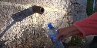 一名女子用塑料瓶从森林里的泉水中取水