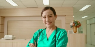 快乐的年轻亚洲女医生或护士穿着绿色的医用外套和听诊器，有自信和成功，交叉手臂微笑着看着镜头。在医院工作的女专科医师。