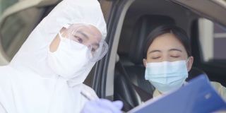 身穿防护服的医务人员对一名司机的口腔拭子进行了冠状病毒covid-19感染检测。