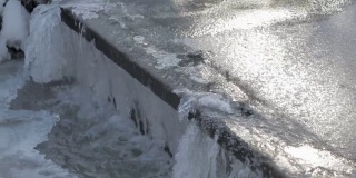 冰冻的水流过一个小水坝的特写镜头。