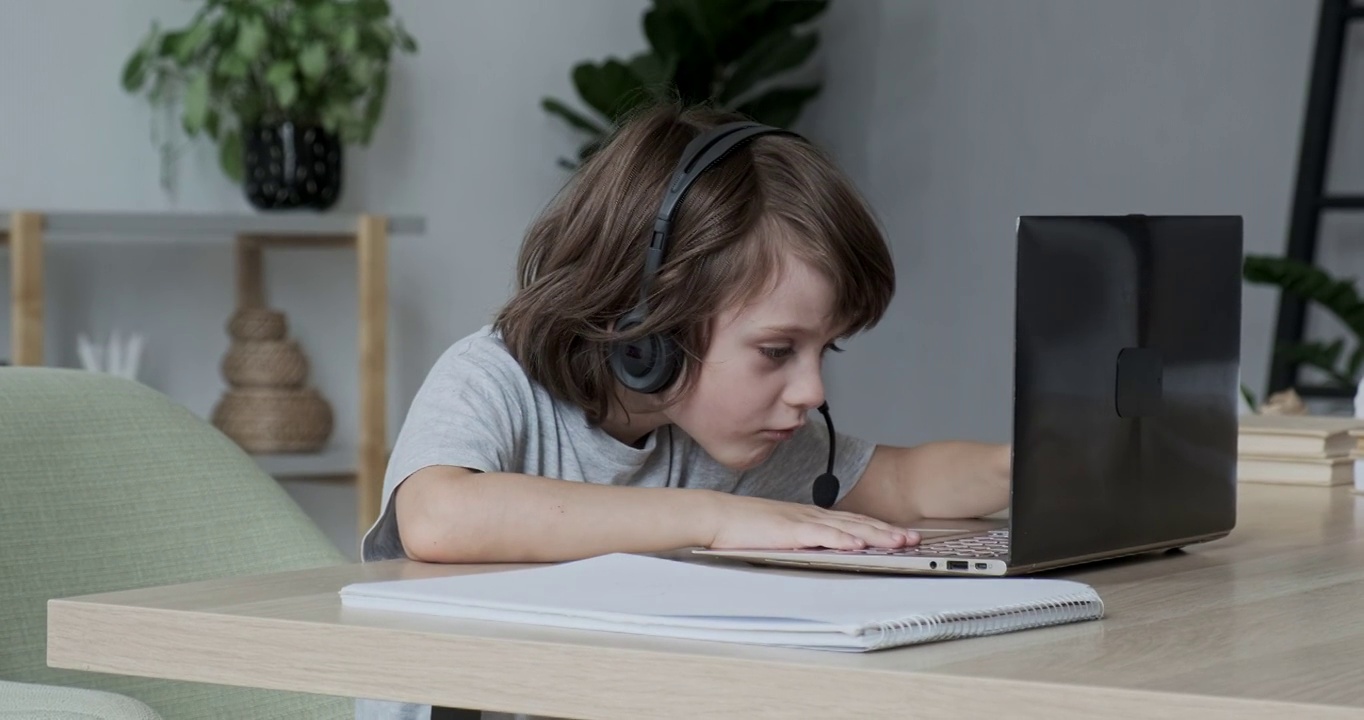 认真专注的男孩通过视频聊天笔记本电脑在线学习。孩子学习电脑
