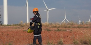 穿着制服的女工程师在风力涡轮机农场工作。