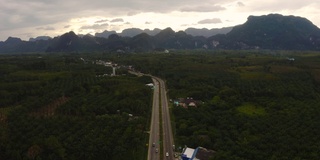 在泰国攀牙湾的红树林和茂密的雨林上空，可以看到多山的岛屿和海洋上引人注目的橙色日出