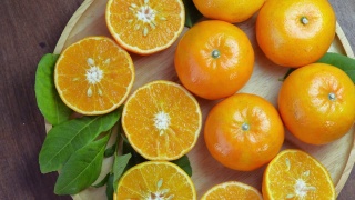 木盘上的鲜橘切片，花园木桌上的木盘上的橘子果。视频素材模板下载