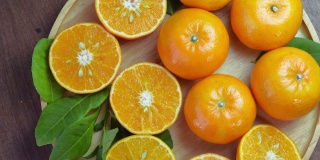 木盘上的鲜橘切片，花园木桌上的木盘上的橘子果。