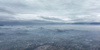 从空中俯瞰，在一个多云的日子里，从空中俯瞰一个美丽的山谷和远处的山脉。