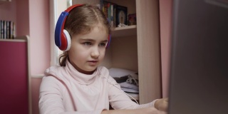 远程学习。一名女学生用笔记本电脑在线学习。学生戴耳机观看网络课程。未来的程序员学习编程。孩子玩电脑游戏。