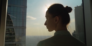 透过摩天大楼的后视镜，沉思的女人在看城市风景