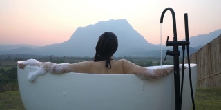 亚洲女人放松在户外沐浴与山景在前面