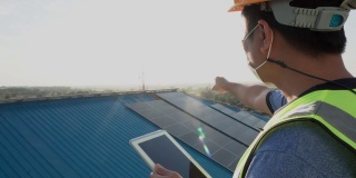 日落时分，一位年轻的亚洲工程师正在用平板电脑检查太阳能光伏板的运行和清洁情况。