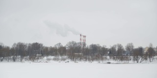 在一个寒冷的日子里，工厂里的烟斗在城市中心抽烟。环境污染。类