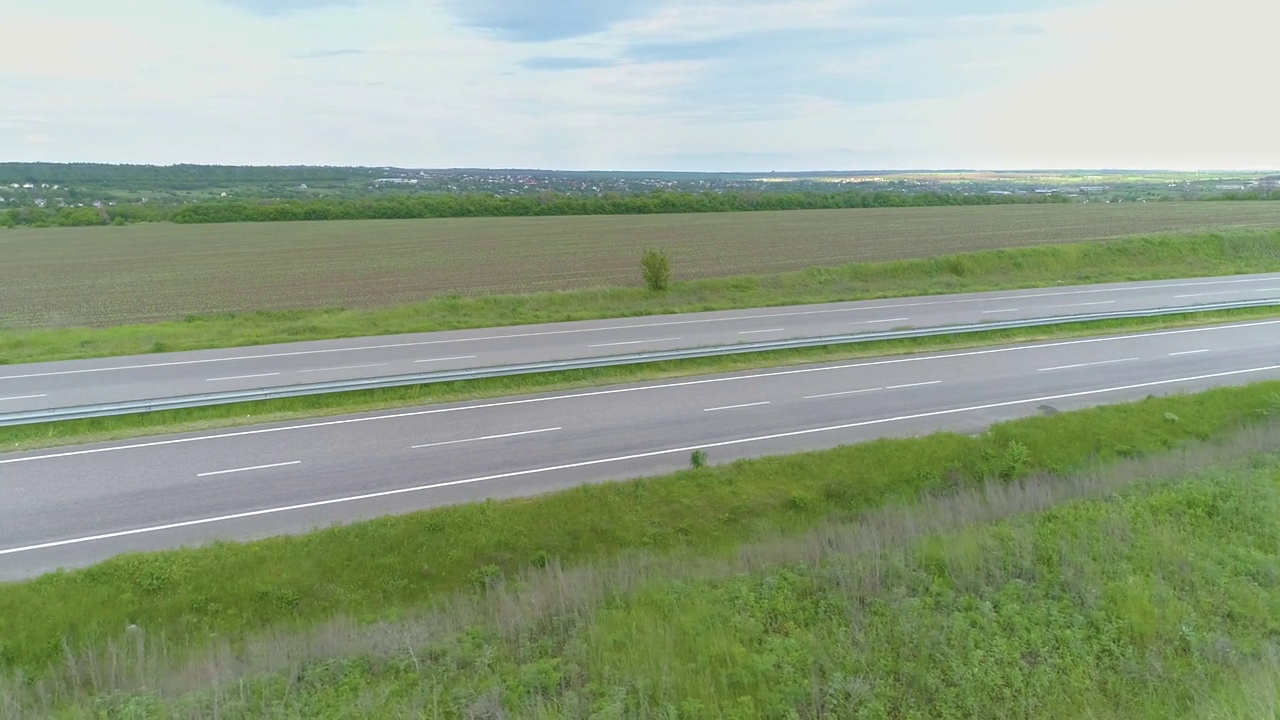 卡车在现代高速公路上骑在绿色的草地上俯瞰。无人机可以看到高速公路上的卡车。