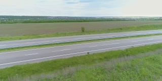 卡车在现代高速公路上骑在绿色的草地上俯瞰。无人机可以看到高速公路上的卡车。