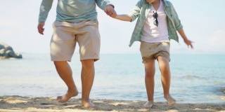 亚洲父亲和儿子跑步和玩耍，在沙滩上一起享受美好时光，慢镜头