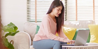 企业家美丽的商业亚洲年轻女性穿粉红色毛衣工作与笔记本电脑在家里。自由职业妇女工作网上销售营销，网上购物在家里。小型企业创业概念