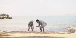 一个亚洲男孩和他的父亲一起在沙滩上玩耍，享受美好时光