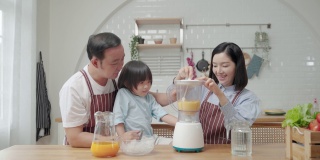 亚洲家庭，爸爸妈妈和儿子帮忙做饭在厨房做冰沙