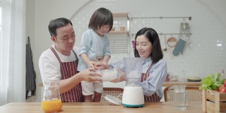 亚洲家庭，爸爸妈妈和儿子帮忙做饭在厨房做冰沙