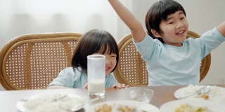 亚洲家庭关系，兄弟姐妹在早餐桌上争夺牛奶。
