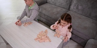 俯视图集中可爱的小白人女孩玩木砖，同时用积木建造木结构。棋盘游戏和精细运动开发、教育理念