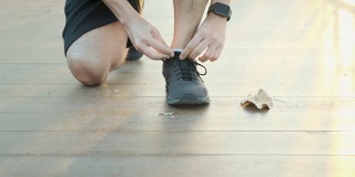 在一个阳光明媚的早晨，一个在公园跑步的人弯下腰去系鞋带