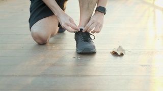 在一个阳光明媚的早晨，一个在公园跑步的人弯下腰去系鞋带视频素材模板下载
