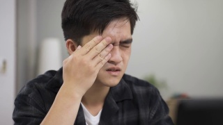 在家里工作的一名亚洲男子因视力不佳而被爆头，他一边盯着电脑屏幕，一边揉眼睛、拍眼睛视频素材模板下载