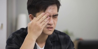 在家里工作的一名亚洲男子因视力不佳而被爆头，他一边盯着电脑屏幕，一边揉眼睛、拍眼睛