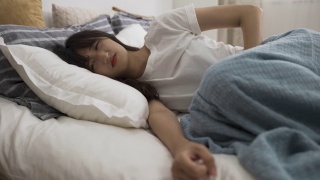 亚洲妇女在家里的卧室里忍受着月经疼痛，蜷缩在床上，抱着自己的肚子。视频素材模板下载