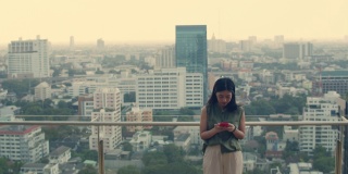 亚洲女性站在楼顶使用智能手机。