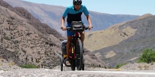 骑着带拖车的自行车的人在安第斯山脉克服了一个困难的关口