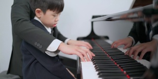 钢琴家在学校的教室里教一个男孩弹钢琴。最喜欢的古典音乐。在学习中快乐和乐趣。身着正式优雅套装的音乐家。教育、练习、放松的理念。