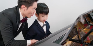 钢琴家在学校的教室里教一个男孩弹钢琴。最喜欢的古典音乐。在学习中快乐和乐趣。身着正式优雅套装的音乐家。教育、练习、放松的理念。