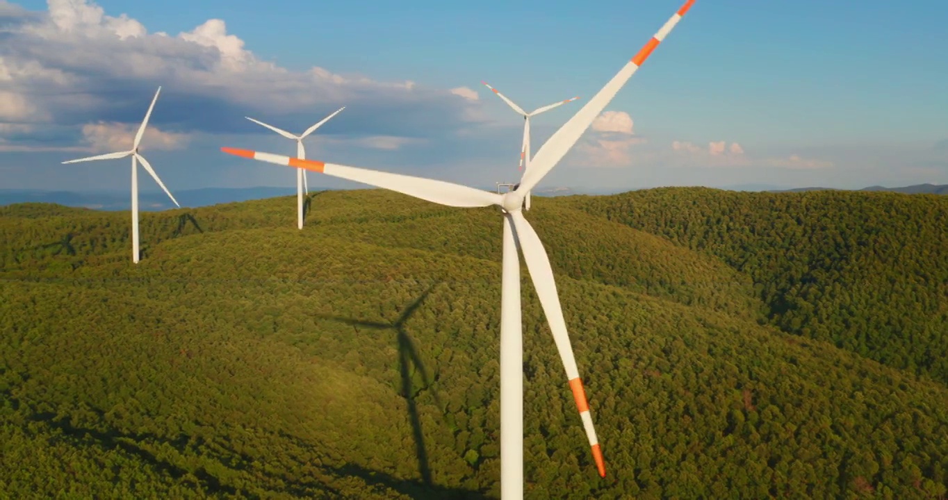 空中特写镜头风力磨坊旋转的力量，并产生可再生能源在绿色生态的方式，以太阳照耀地球。