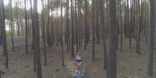 空中镜头。一名年轻女子在森林里的跑步机上跑步。