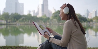亚洲女人喜欢在早晨在城市公园听音乐和看书，人们在城市的自然环境中放松。