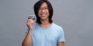 年轻英俊的亚洲男子出示信用卡
