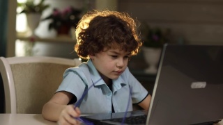 一个戴眼镜的男孩坐在笔记本电脑前，因疲劳而揉眼睛视频素材模板下载