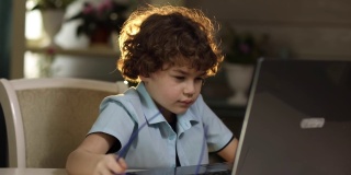 一个戴眼镜的男孩坐在笔记本电脑前，因疲劳而揉眼睛