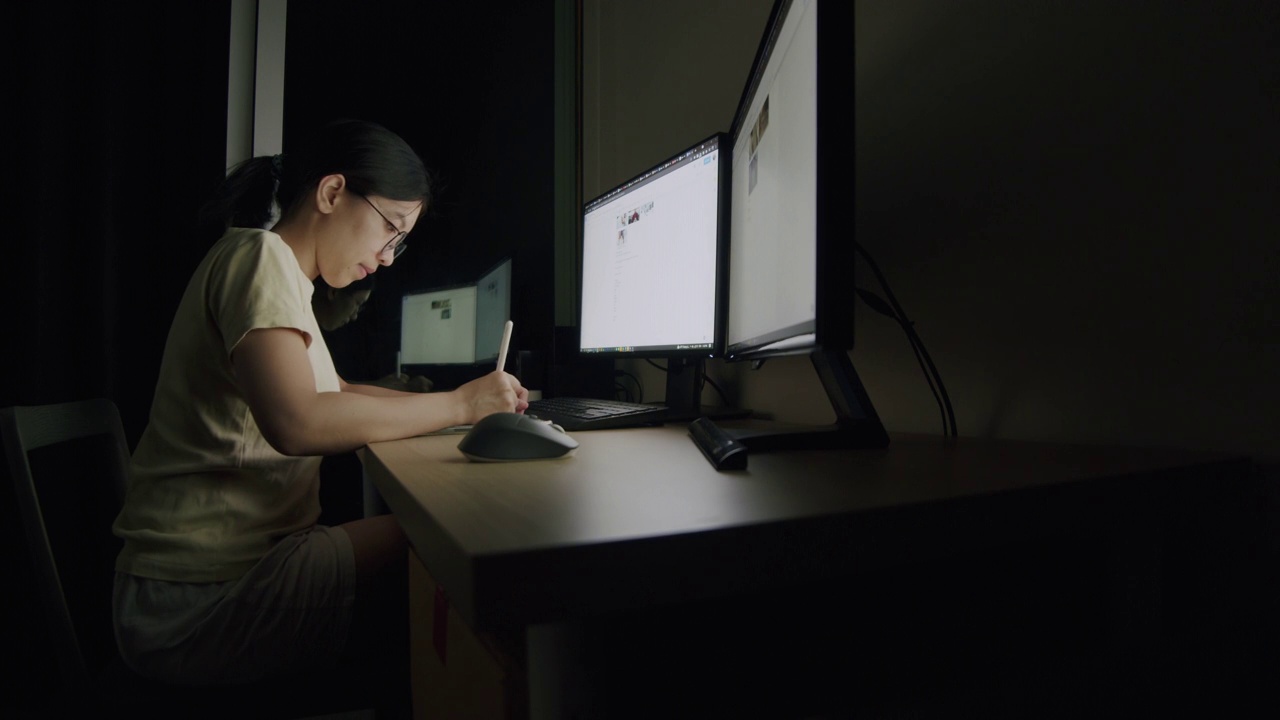 亚洲女商人Candid晚上在家庭办公室用平板电脑写作。