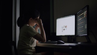 亚洲女性工作到很晚，在家里的暗房里感到困倦。视频素材模板下载