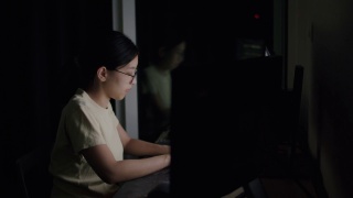 亚裔自由职业妇女，戴着眼镜，在电脑上敲击键盘，搜索资料。视频素材模板下载