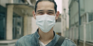 一名亚洲男子戴着口罩站在城市街道上，以防止空气污染和covid-19大流行。