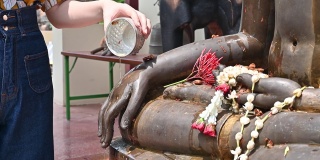 泰国泼水节期间，妇女用手向佛像泼香水。