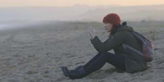 一个美丽的女人坐在沙滩上的电影镜头