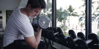 图为，一名亚洲男子上午在度假村健身中心进行哑铃重量训练。