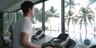 一名亚洲男子早上在度假健身中心的跑步机上锻炼。